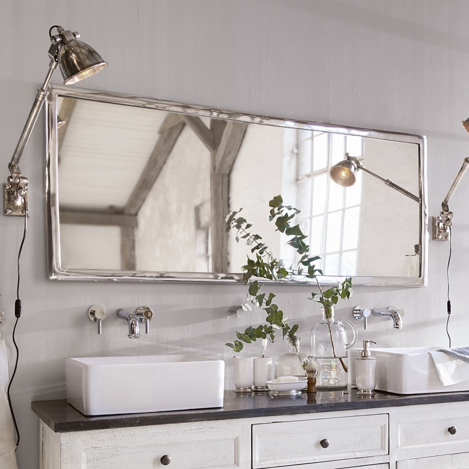 Miroir Kaplin Grand miroir rectangulaire à cadre métallique au-dessus d'un lavabo blanc sur un plan noir dans une salle de bain
