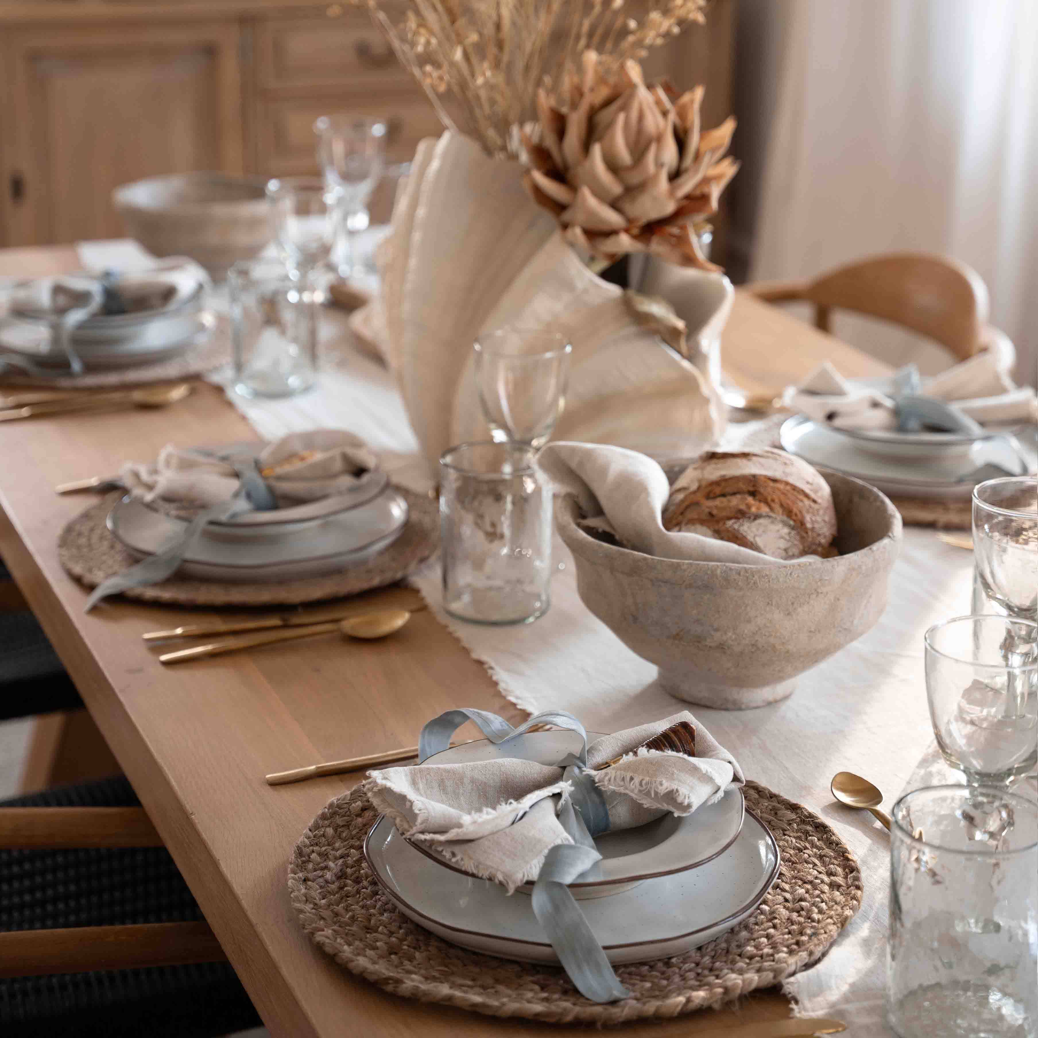 Décoration de table avec coquillage naturel et pain dans un bol en lin sur une table en bois