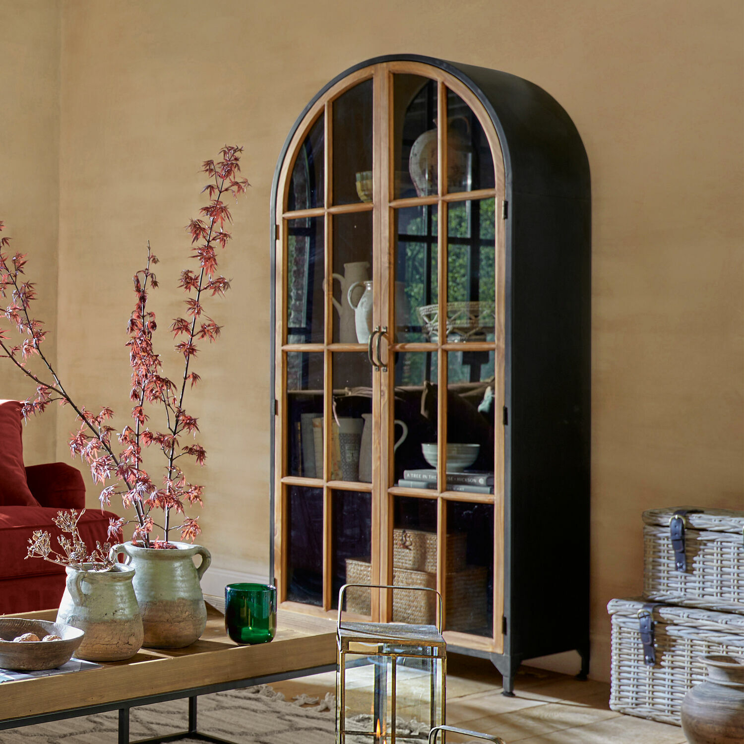 Armoire Mardilly Armoire avec corps en métal noir arrondi et portes vitrées en bois dans un salon chaleureux
