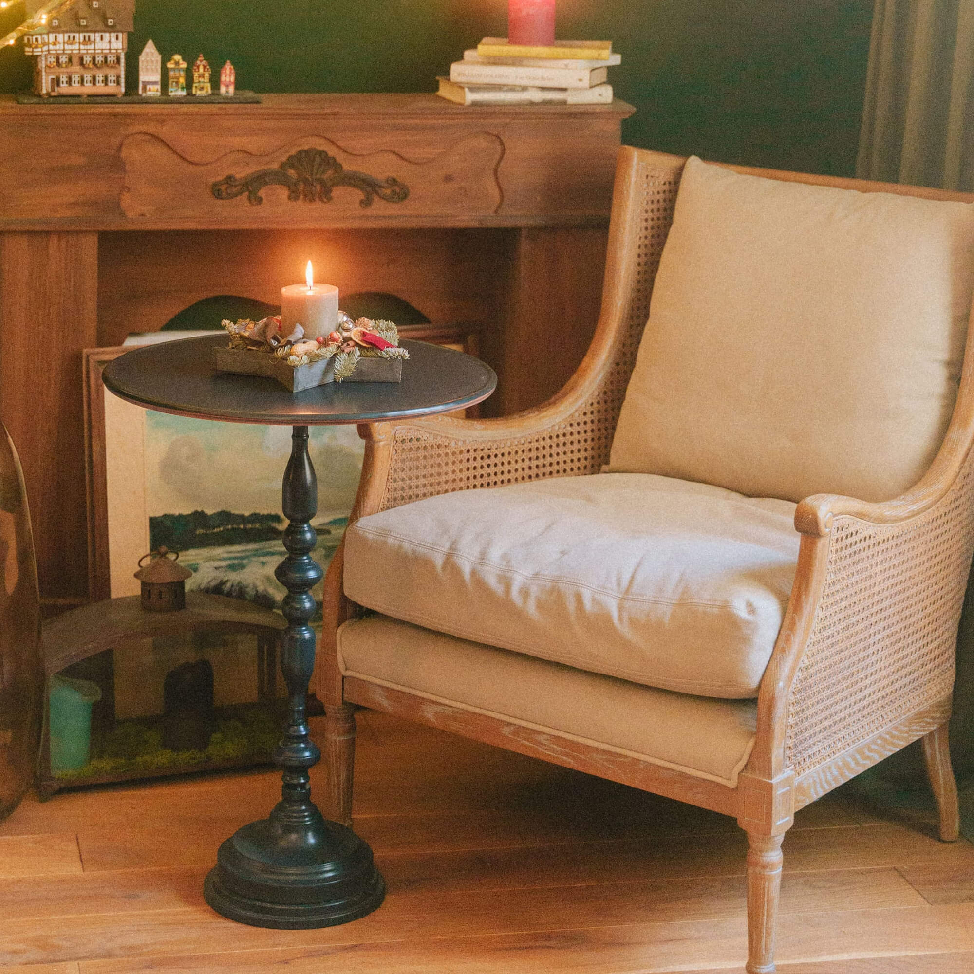 Fauteuil beige en bois avec table noire et bougie allumée dans un intérieur chaleureux