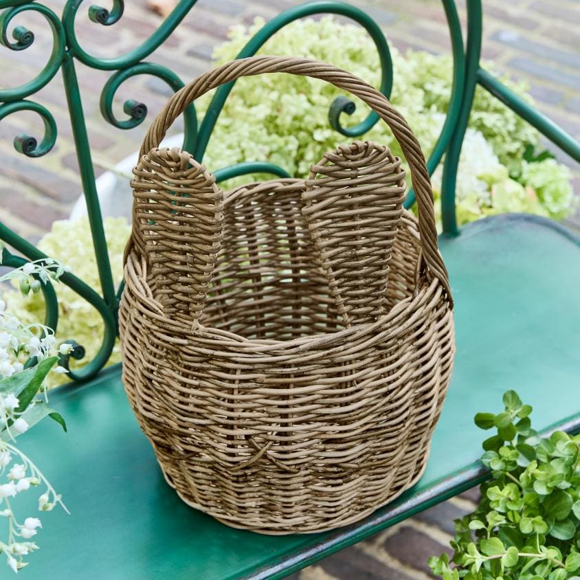 Panier en osier naturel avec anses, posé sur un banc vert, décoration d'extérieur rustique