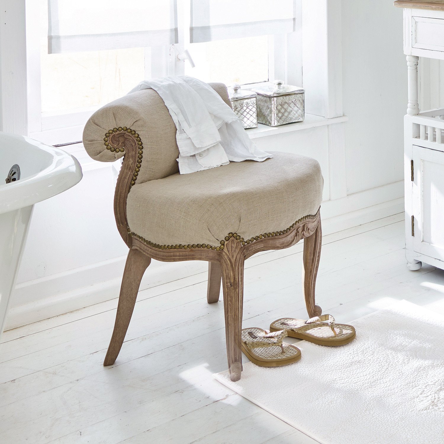 Fauteuil Rivel Fauteuil beige en tissu avec cadre en bois sculpté dans une salle de bain lumineuse