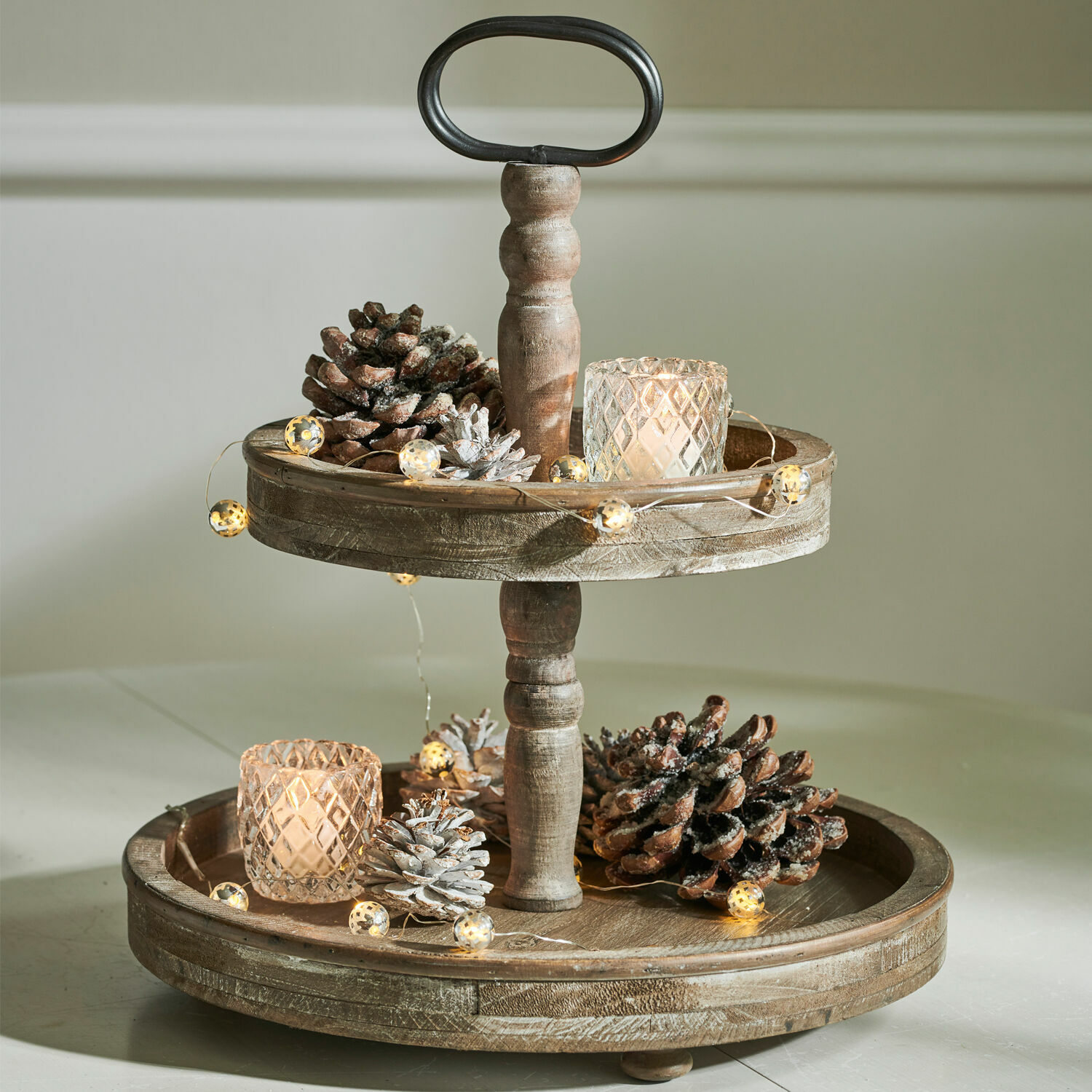Présentoir en bois à deux niveaux décoré de pommes de pin et bougies LED pour ambiance chaleureuse