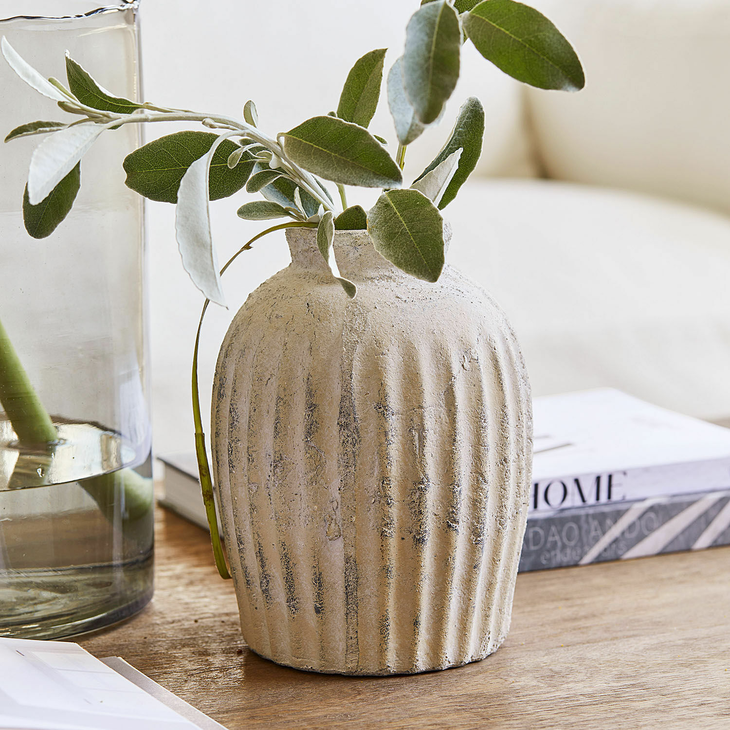 Vase Melissa Vase en céramique beige texturé avec feuillage vert sur une table en bois pour décoration intérieure