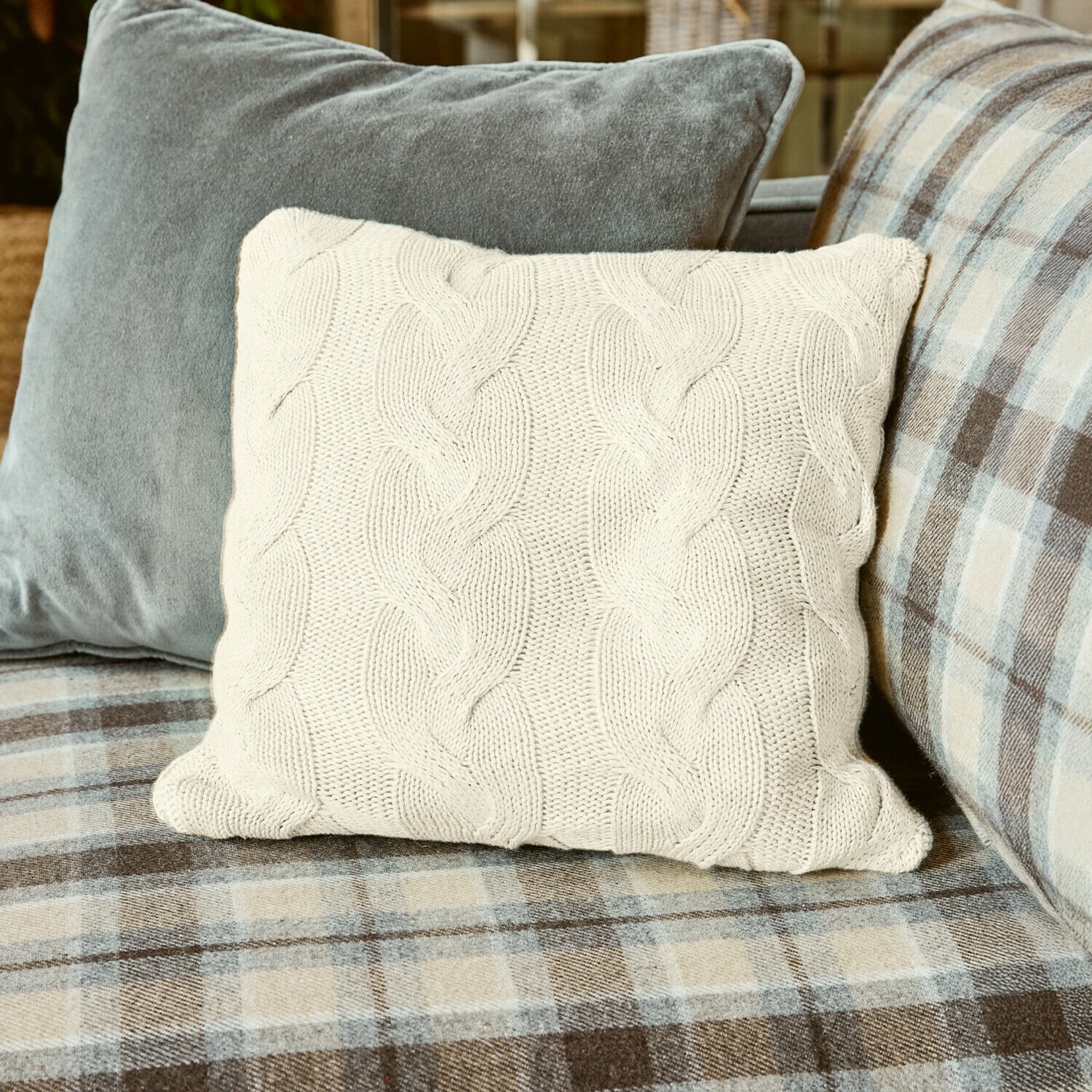 Housse de coussin Arnhem Coussin beige en maille torsadée sur canapé à carreaux, accessoire déco confortable