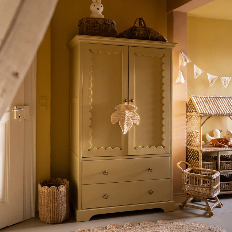 Armoire en bois beige avec panneaux décoratifs et deux tiroirs dans une chambre d'enfant chaleureuse