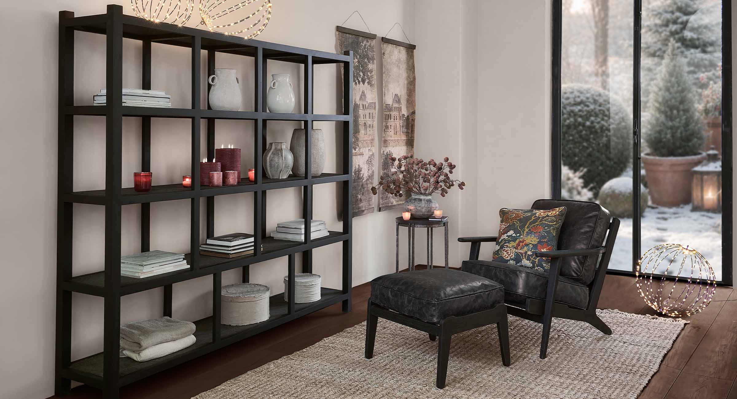 Étagère noire en bois avec décorations dans un salon cosy avec vue sur jardin d'hiver enneigé