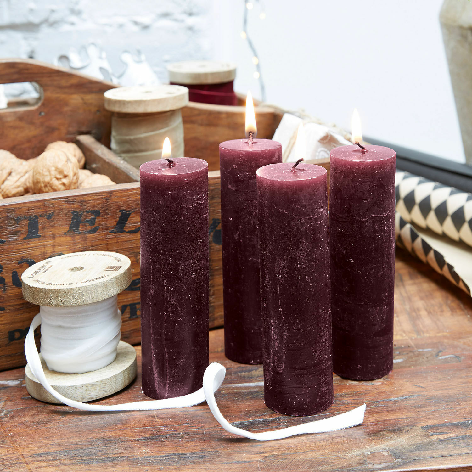 Lot de 4 bougies Muriel Quatre bougies bordeaux en cire sur une table en bois avec ruban décoratif et noix