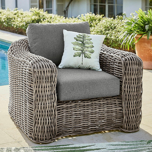 Fauteuil de jardin en osier gris avec coussins gris et coussin décoratif à motif feuille verte