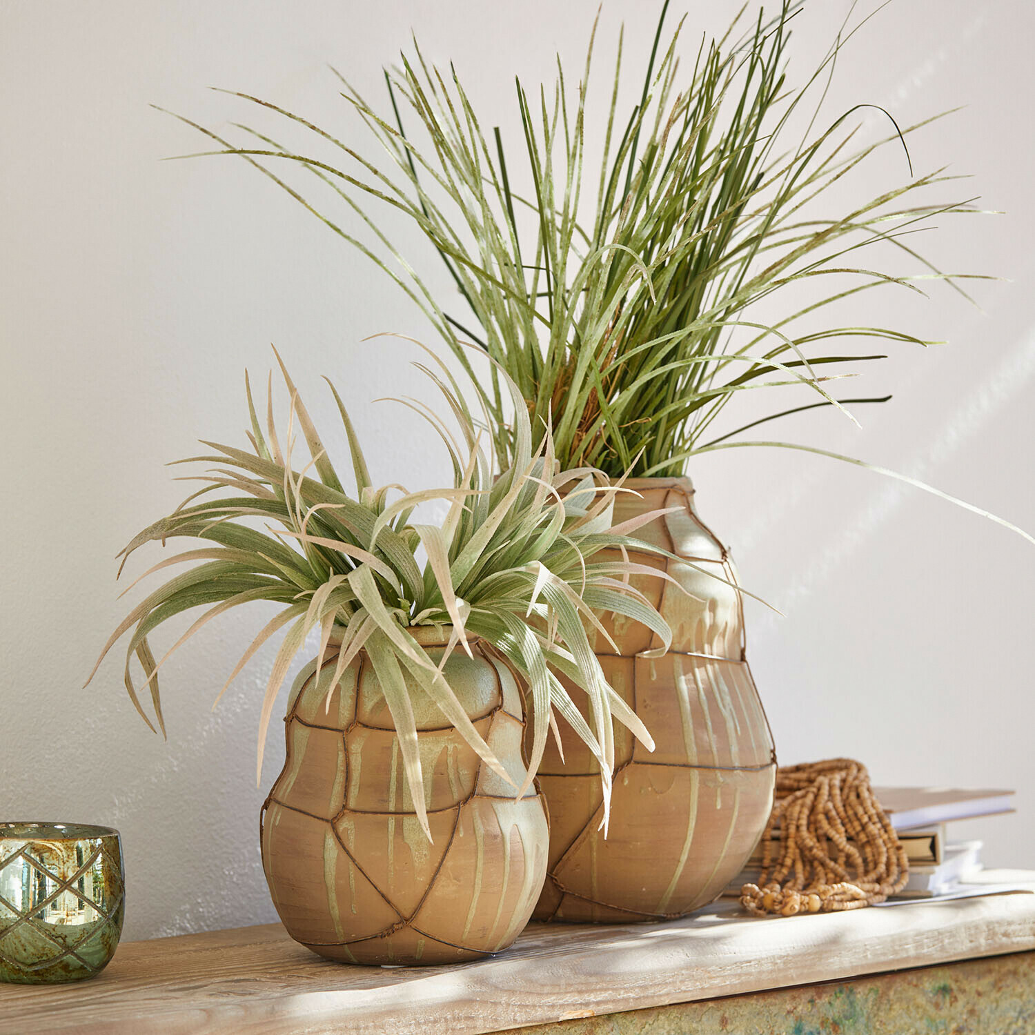 Deux vases en céramique beige avec plantes vertes décoratives sur une table en bois clair