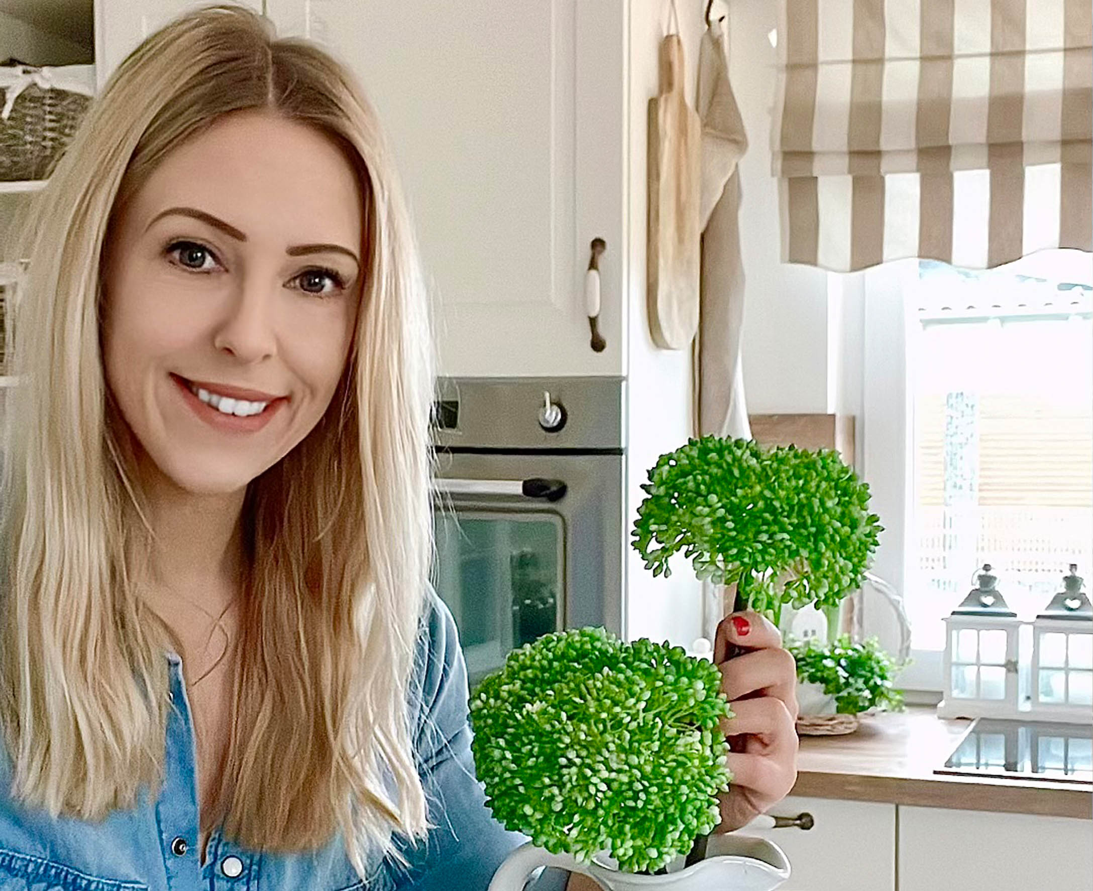 Femme dans une cuisine tenant des fleurs décoratives vertes dans un pichet blanc, style rustique