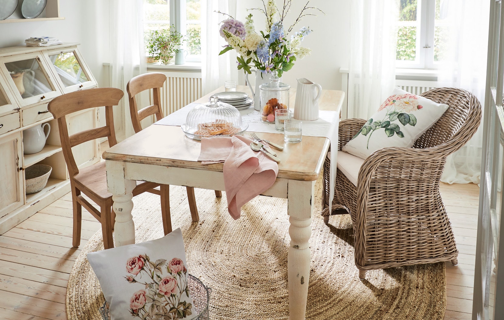 Salle à manger shabby chic avec table en bois, fauteuil en osier et décoration florale