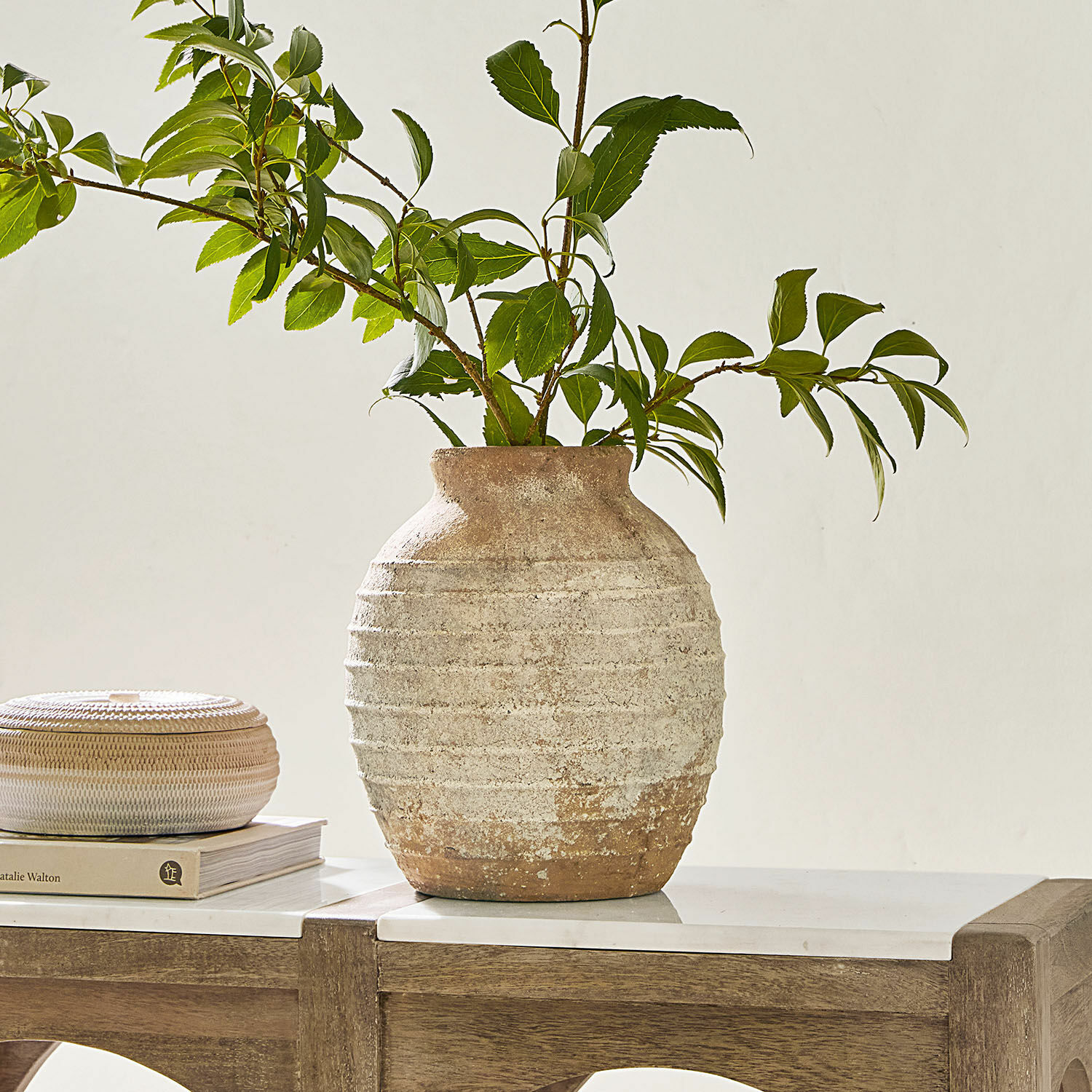 Vase Sibinna Vase rustique en céramique beige et marron avec branches vertes sur une table en bois