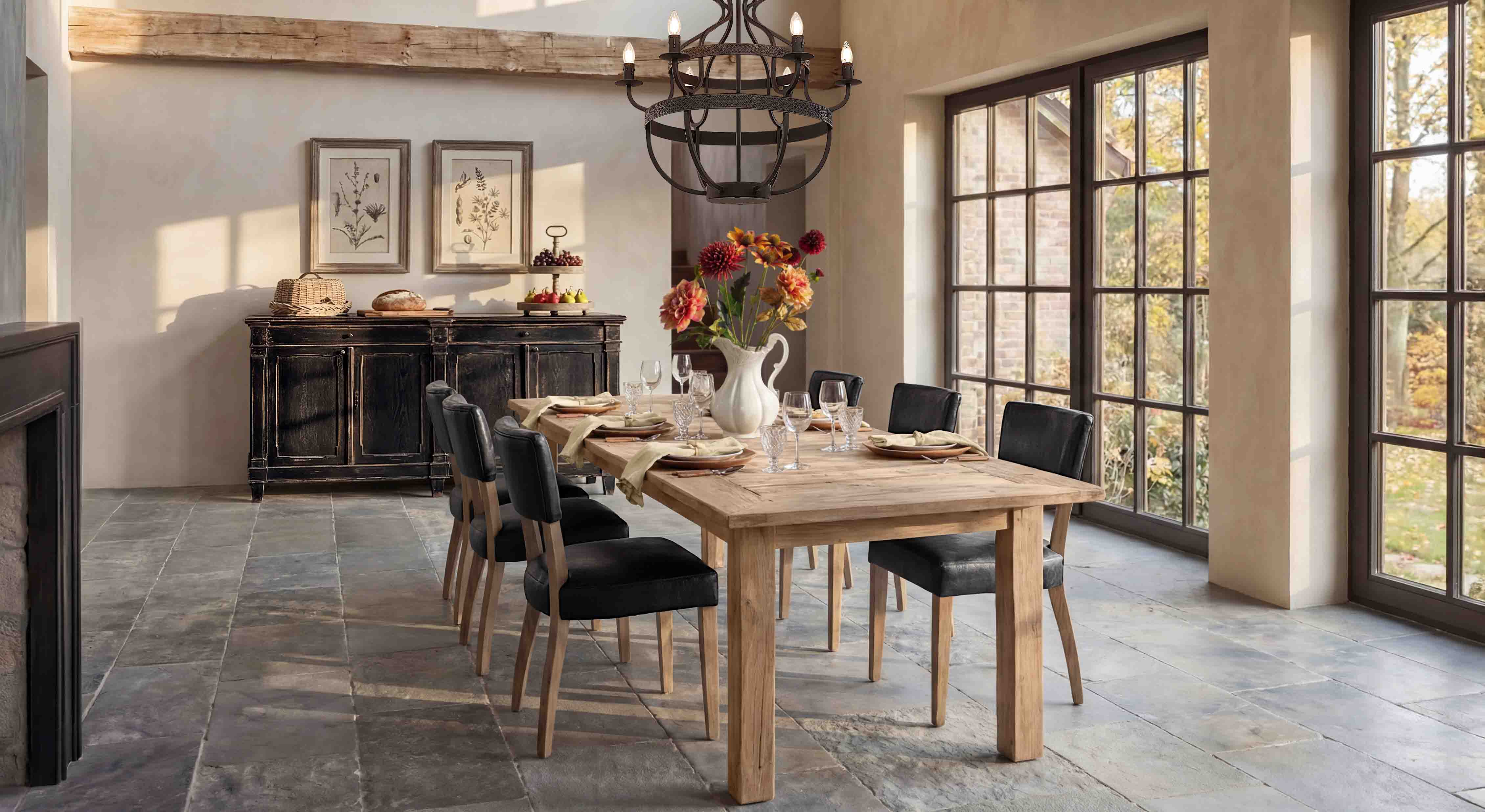 Salle à manger avec table en bois clair et chaises noires sous une grande fenêtre lumineuse