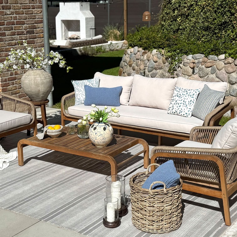 Ensemble de mobilier de jardin en bois avec canapé beige et coussins à motifs bleus sur tapis rayé