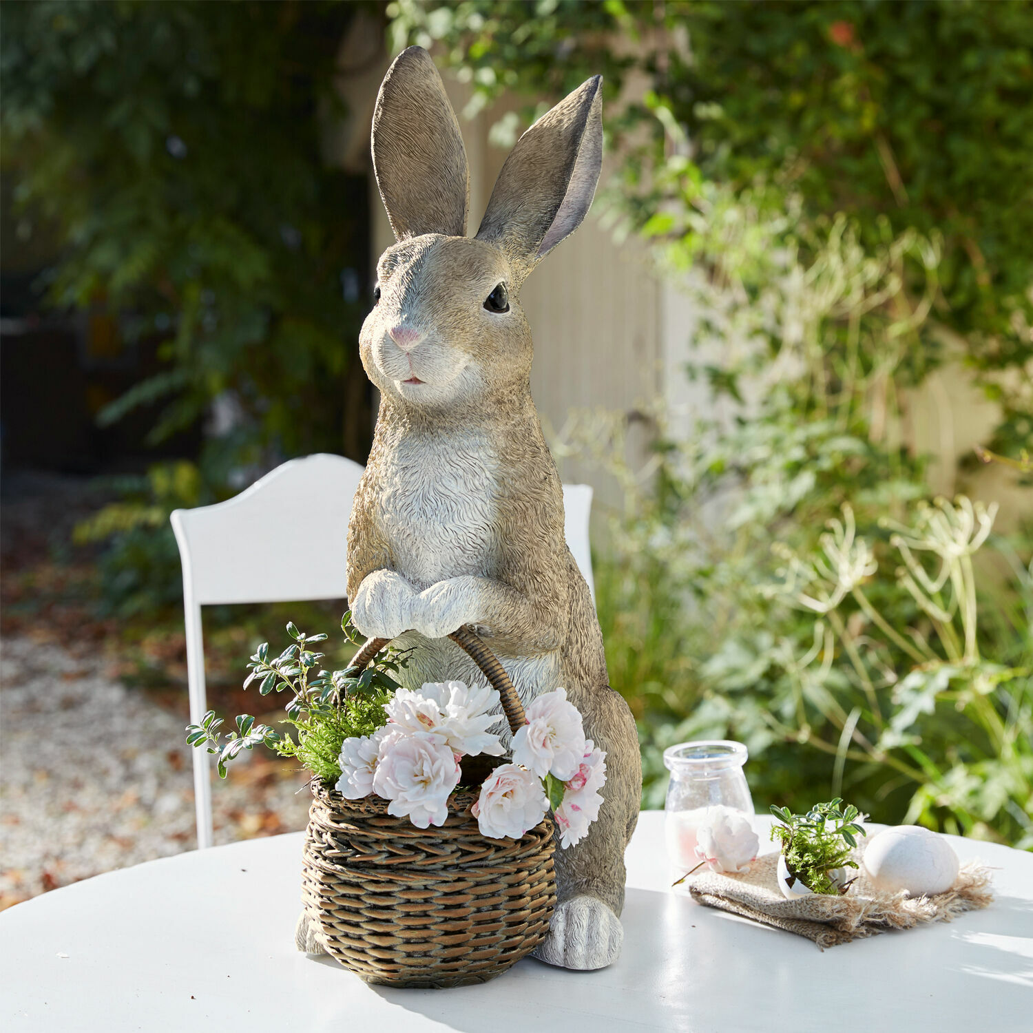 Lapin avec corbeille Alais Lapin décoratif en résine avec panier en osier et fleurs blanches sur une table extérieure