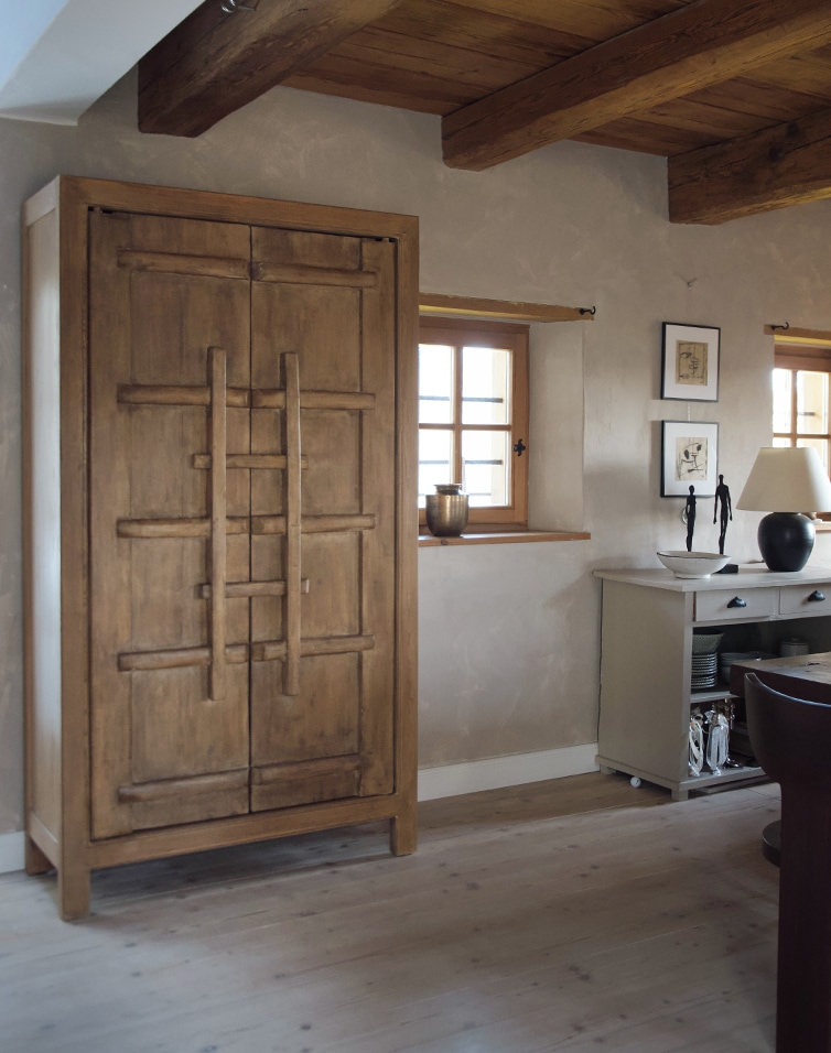 Armoire en bois couleur naturelle dans un intérieur rustique avec poutres apparentes et sol clair