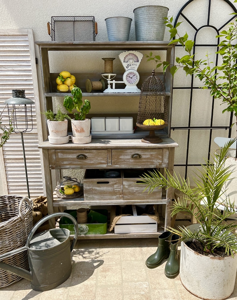 Meuble en bois rustique avec étagères et tiroirs style vintage, décorations de jardin sur terrasse ensoleillée