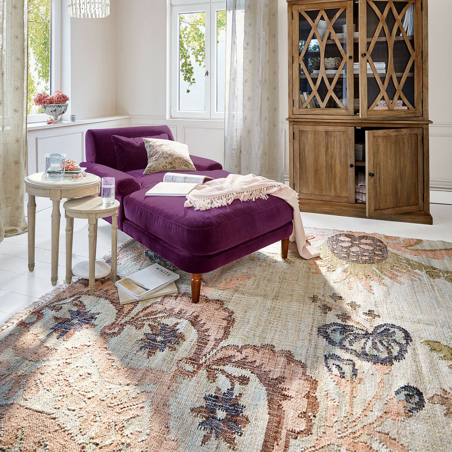 Tapis Amélorie Chaise longue en velours violet dans un salon lumineux avec meuble en bois et tapis décoratif