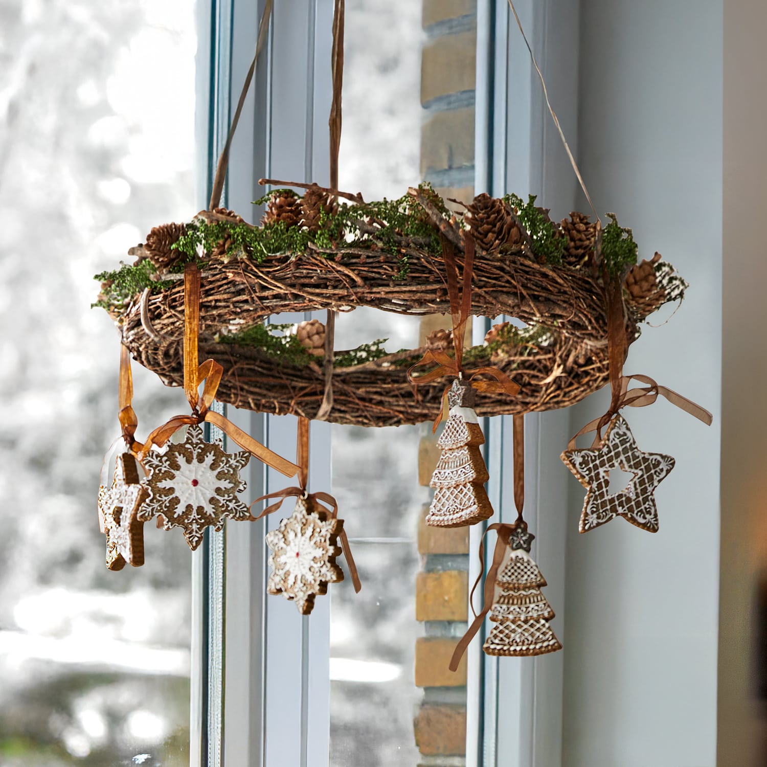 Couronne de Noël en branches avec pommes de pin et décorations en pain d'épice suspendues en forme d'étoile et sapin
