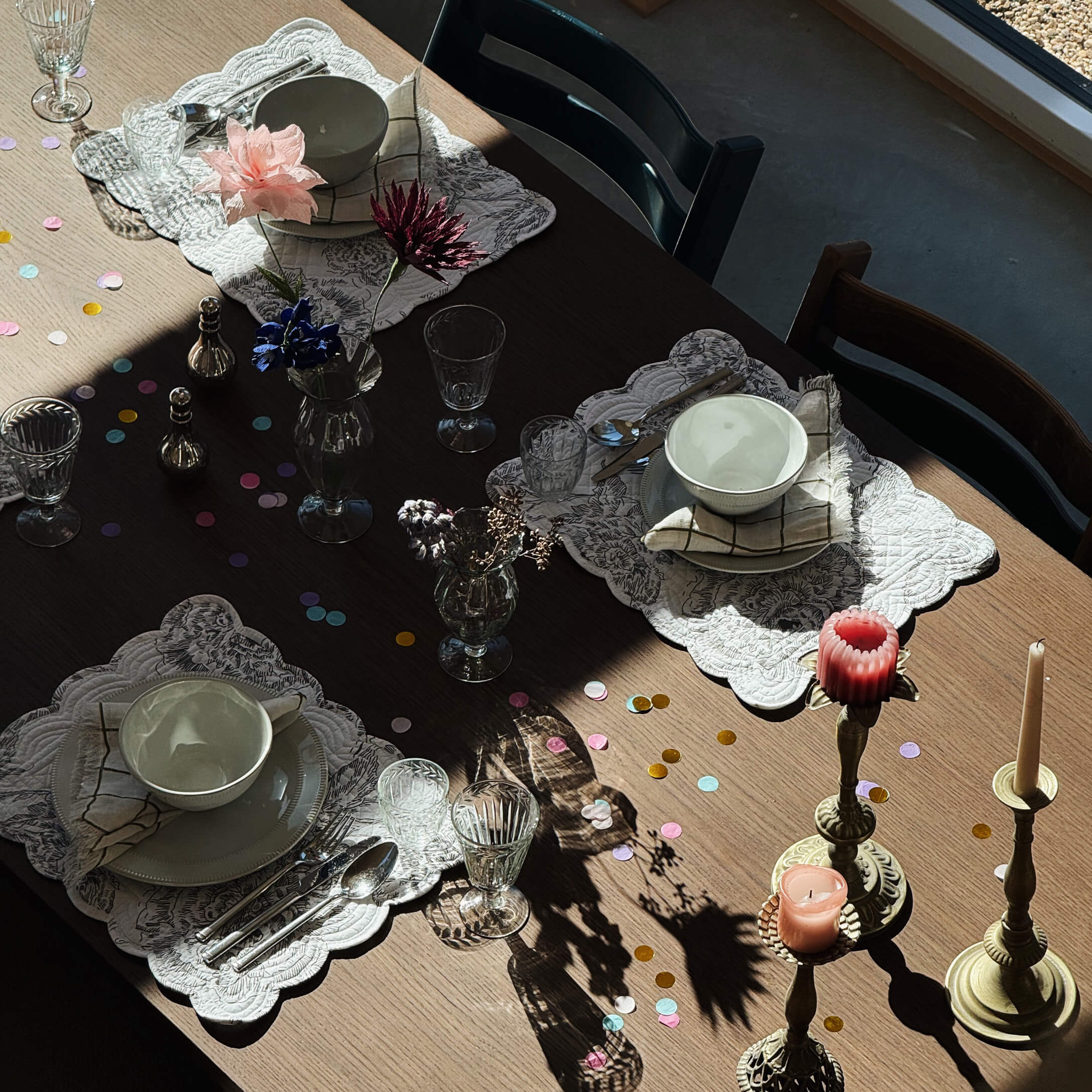 Table en bois avec bols en céramique blanche, verres et bougies sur chandeliers en laiton