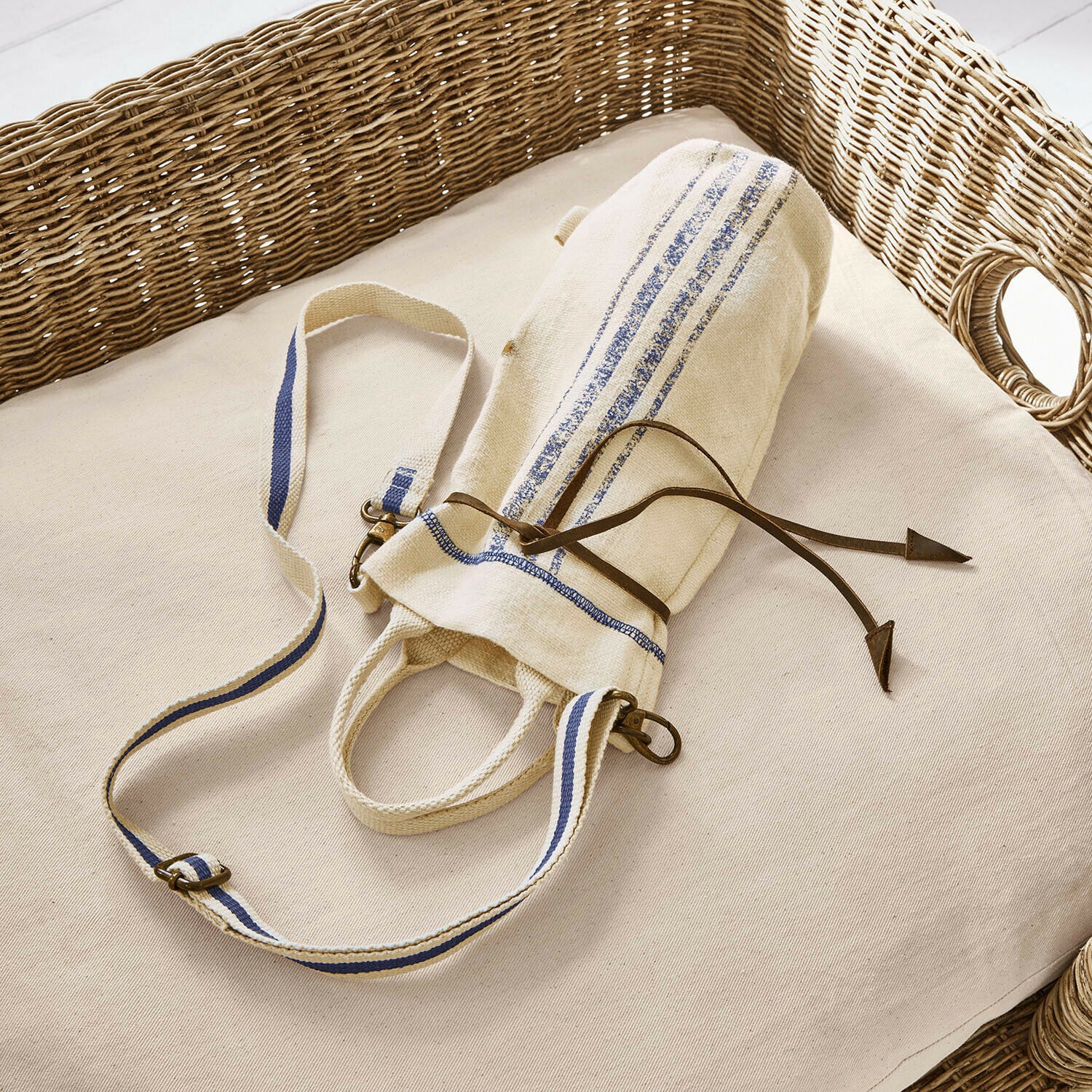 Sac pour bouteille Pawera Sac en coton beige avec bandes bleues et cordon en cuir sur coussin clair avec dossier en osier