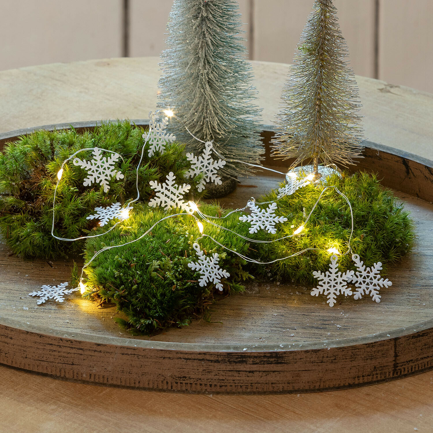 Guirlande lumineuse à LED Azmira Guirlande décorative avec flocons de neige blancs et lumières LED sur mousse verte sur plateau en bois