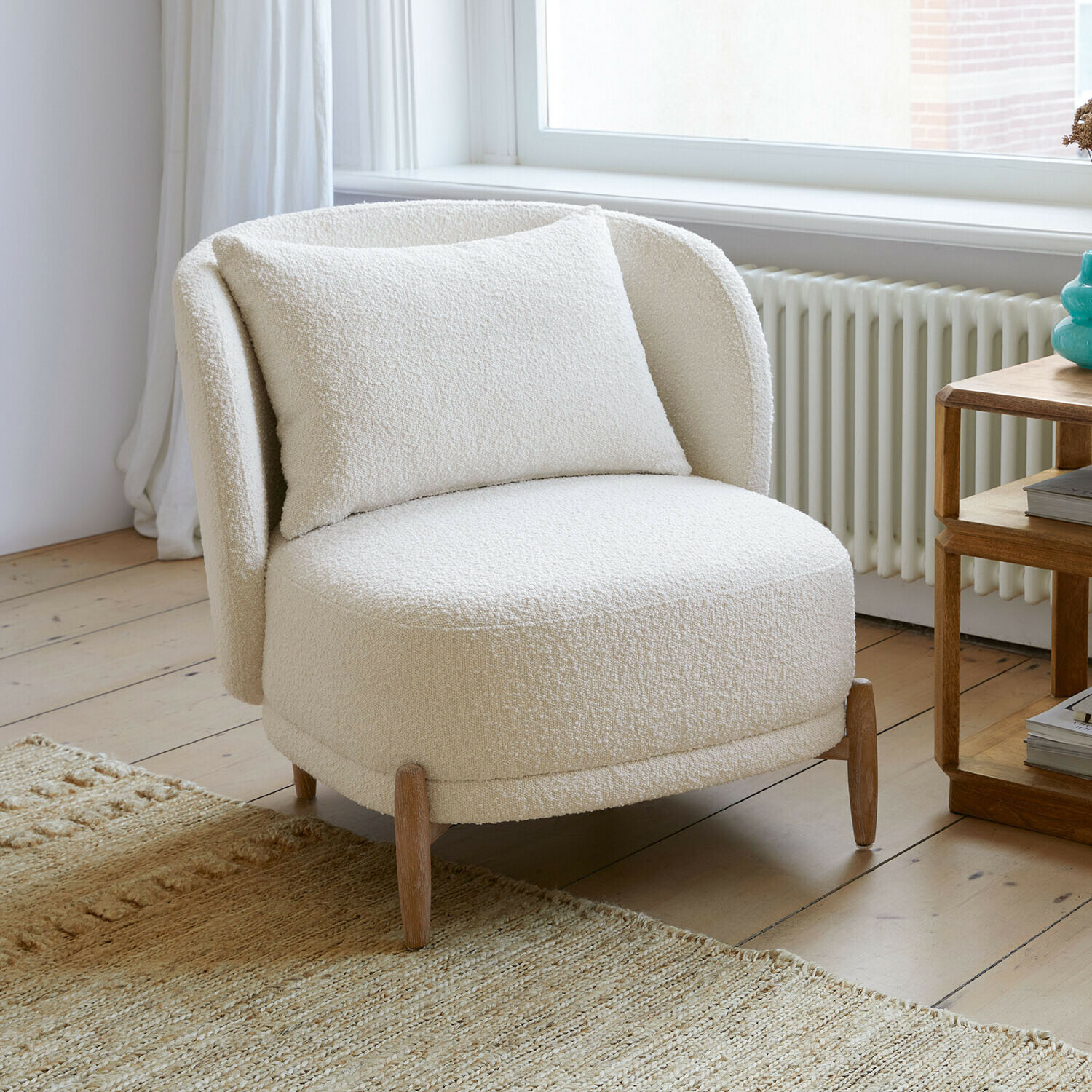 Fauteuil Thamira Fauteuil blanc en tissu bouclé doux avec pieds en bois dans un salon lumineux