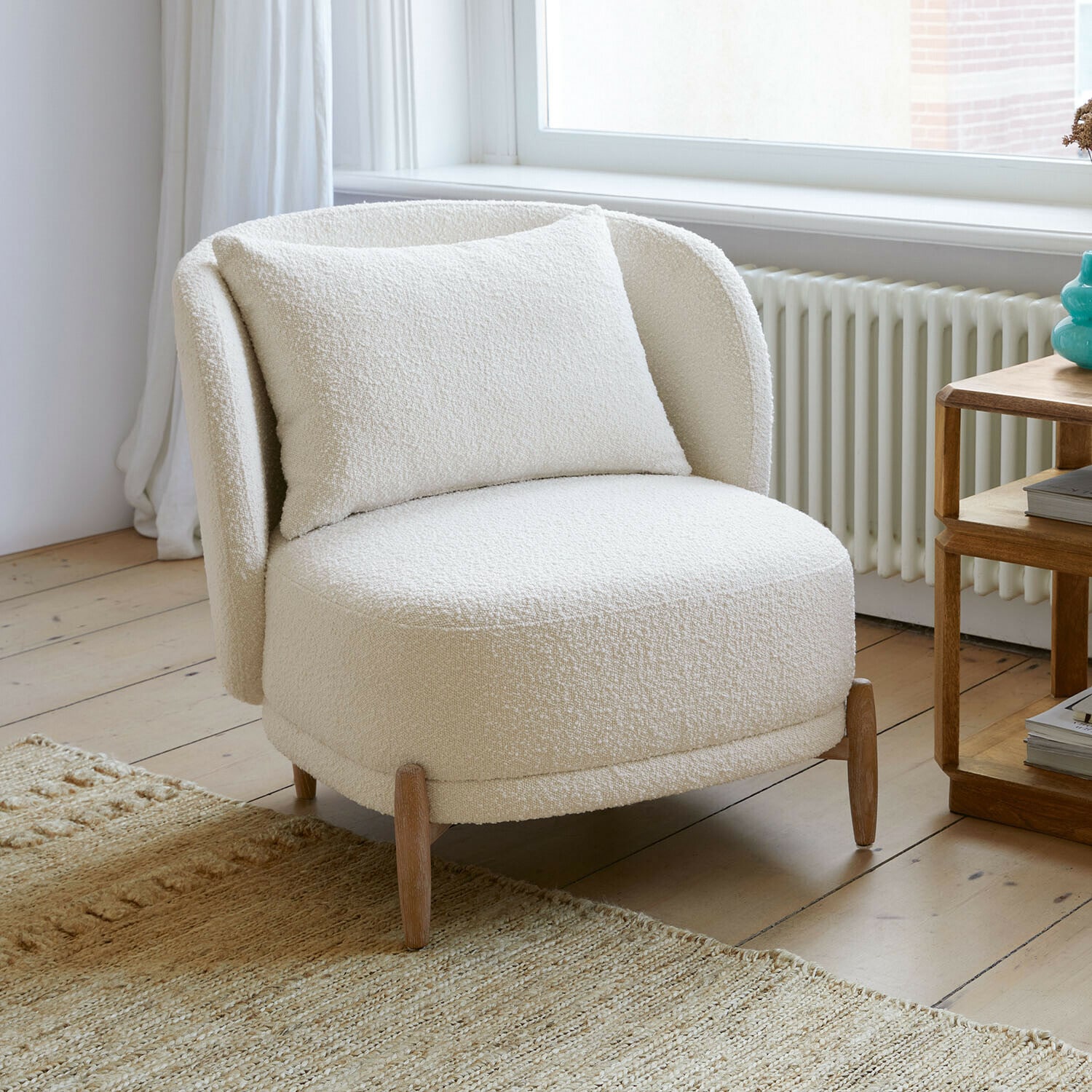 Fauteuil Thamira Fauteuil blanc en tissu bouclé doux avec pieds en bois dans un salon lumineux