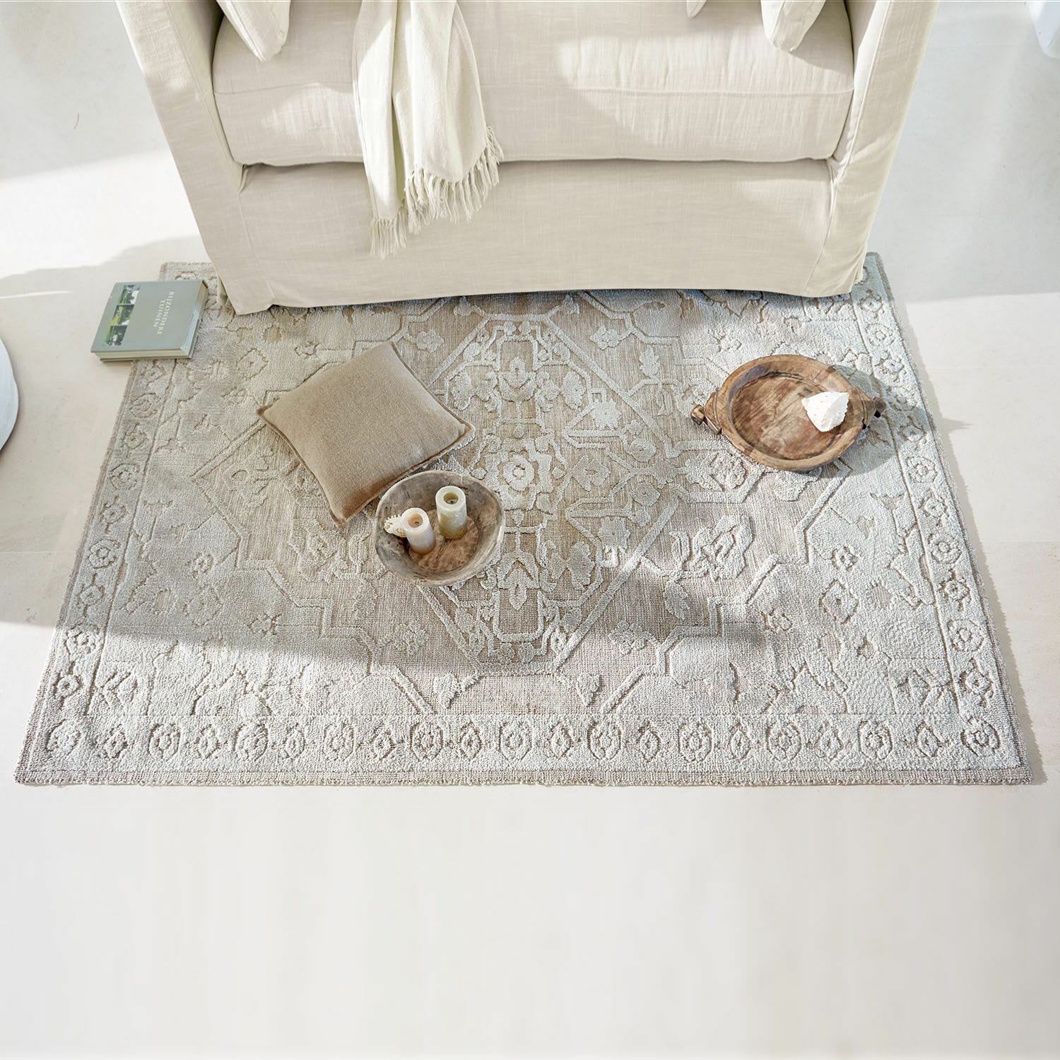 Tapis Armidale Tapis beige à motif délicat sous un canapé clair avec coussin et décorations au sol