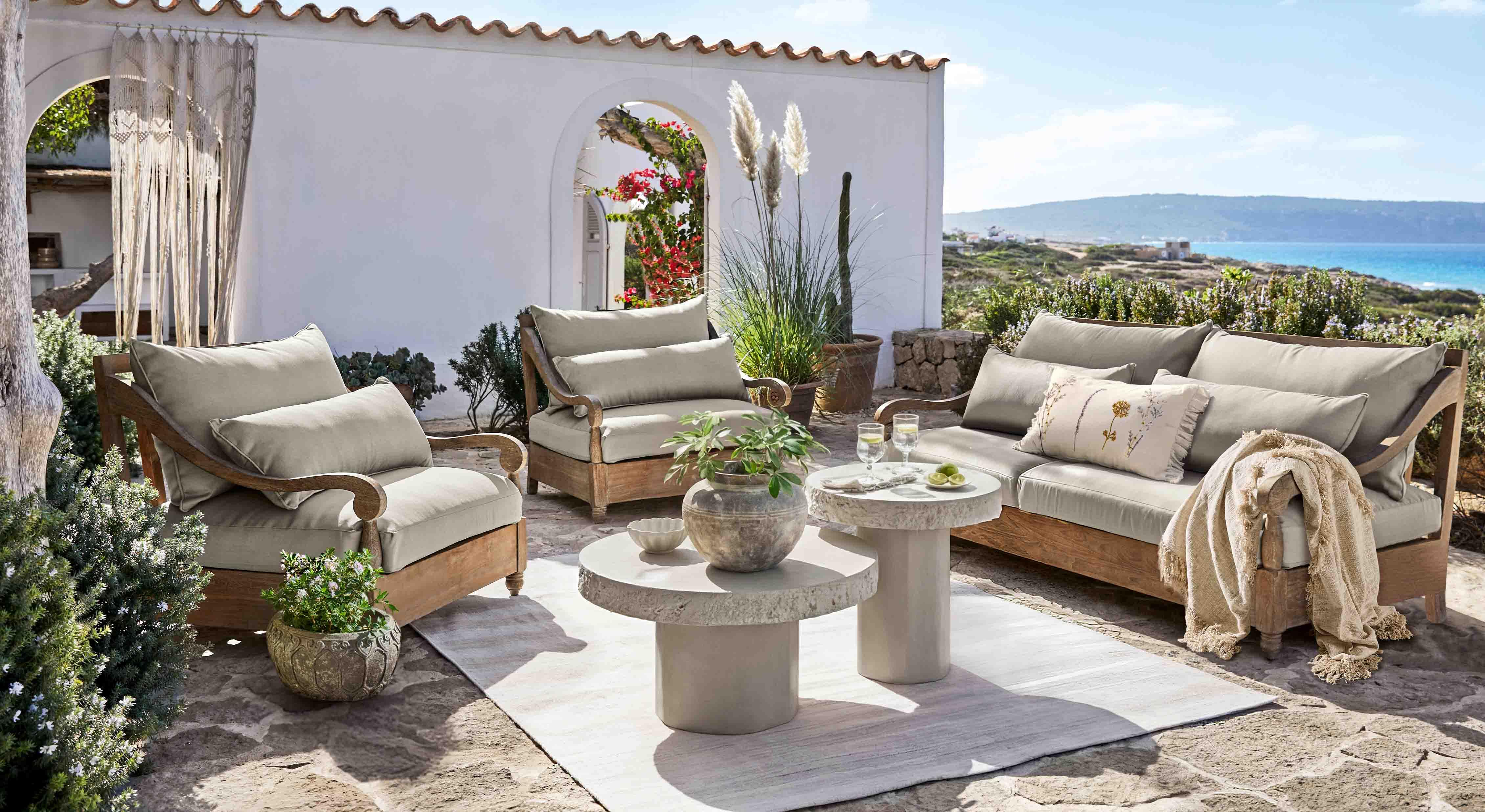 Ensemble de mobilier de jardin en bois avec coussins gris sur terrasse face à la mer
