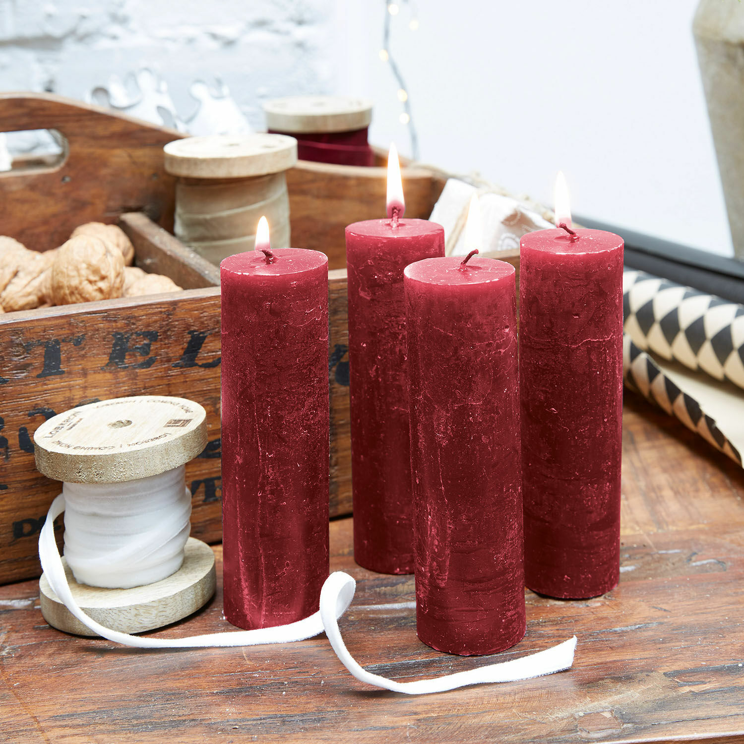 Lot de 4 bougies Muriel Quatre bougies rouges en cire sur une table en bois avec bobines décoratives et noix