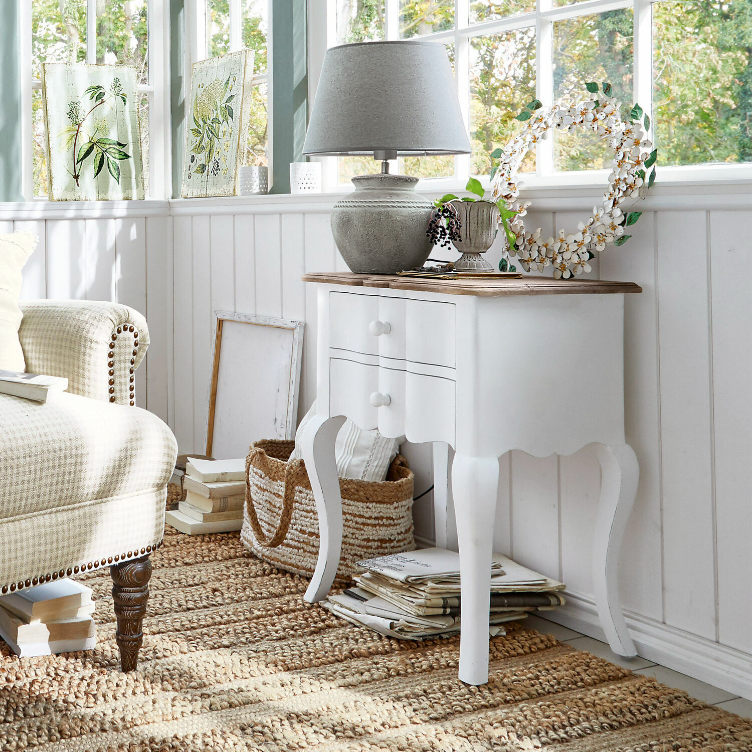 Table d'appoint Fairchild Table d'appoint blanche en bois avec deux tiroirs et plateau en bois dans un salon lumineux style vintage