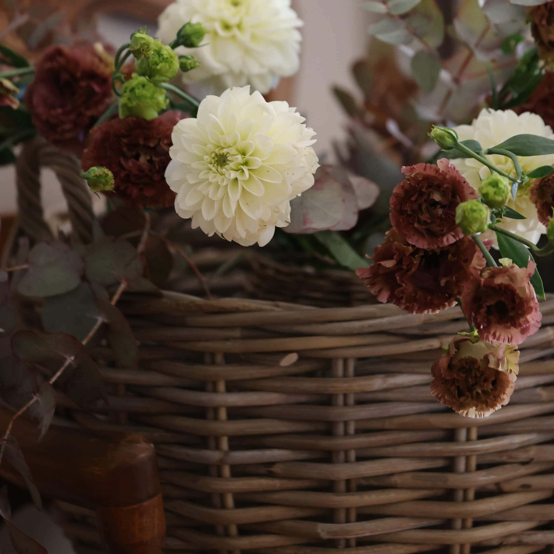 Bouquet de fleurs crème et bordeaux dans un panier en osier pour décoration intérieure