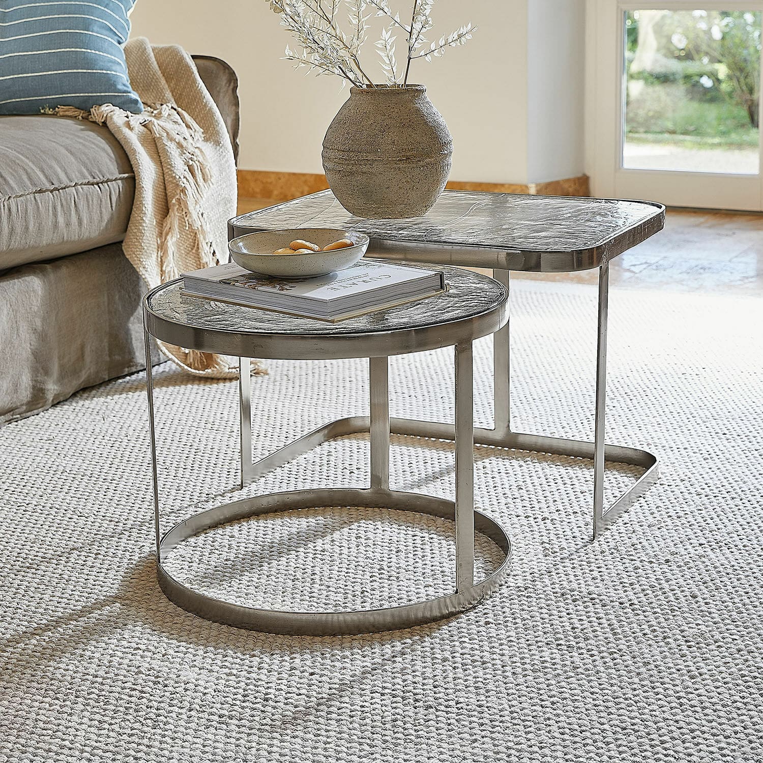 Lot de 2 tables basses Yvelissel Ensemble de deux tables basses avec plateau en verre et cadre métallique argenté sur tapis clair