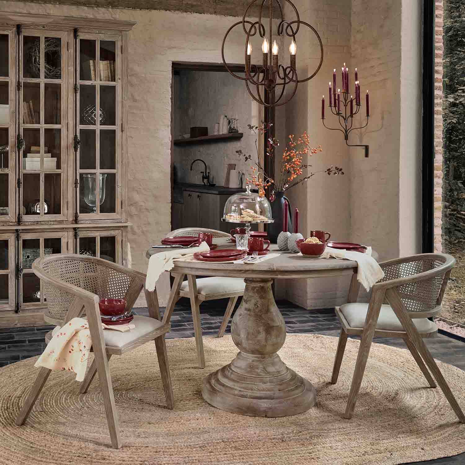 Salle à manger avec table ronde en bois et chaises en rotin naturel, décorations bordeaux élégantes