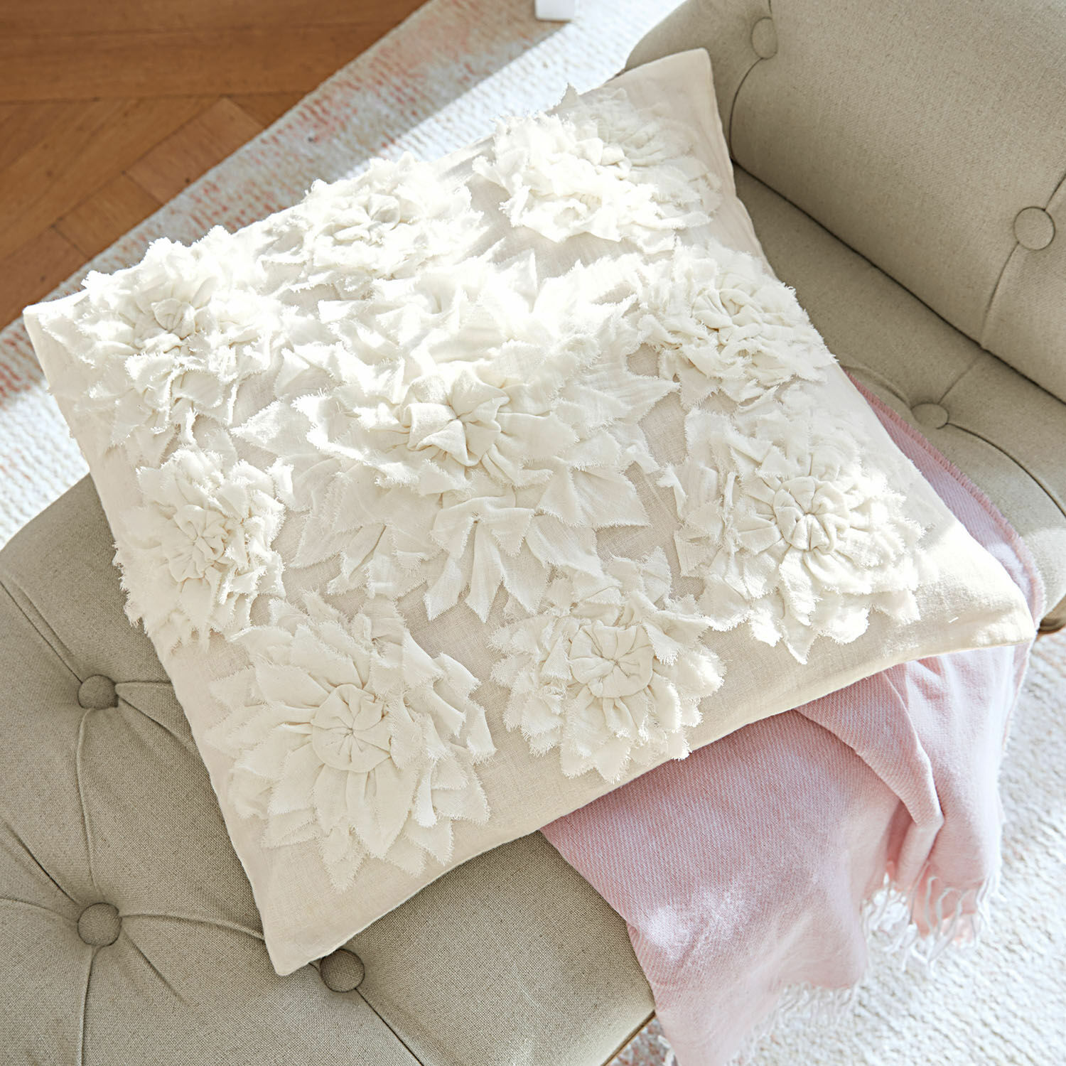 Housse de coussin Dorevil Coussin décoratif beige avec appliques florales en tissu sur un canapé gris avec une couverture rose