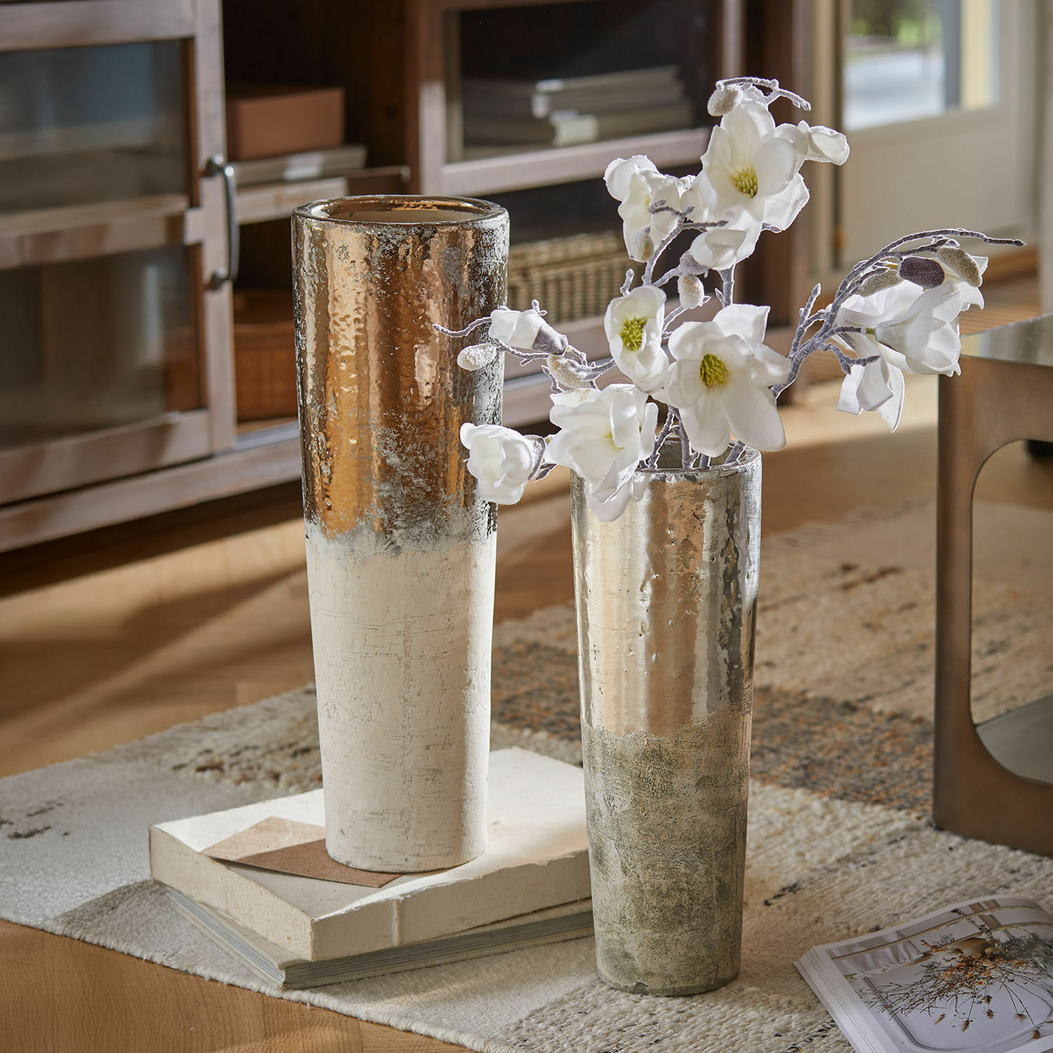 Lot de 2 vases Tameena Deux grands vases en céramique blanc et argent posés sur un tapis avec des fleurs blanches dans un salon