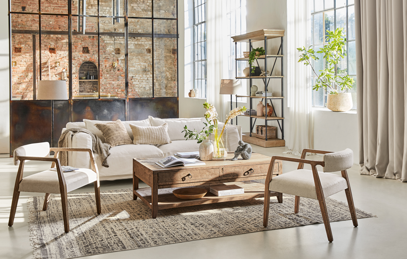 Salon lumineux style loft avec table basse en bois et canapé crème sur tapis texturé