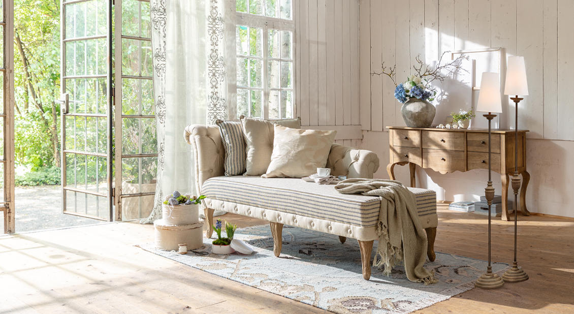 Chaiselongue beige en tissu avec pieds en bois et coussins dans un salon lumineux au style naturel