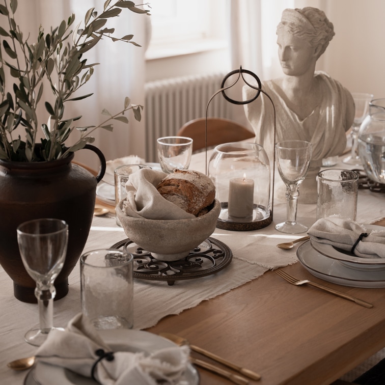 Table rustique avec bol en pierre pour pain, bougie sous cloche et statue en pierre blanche décorative