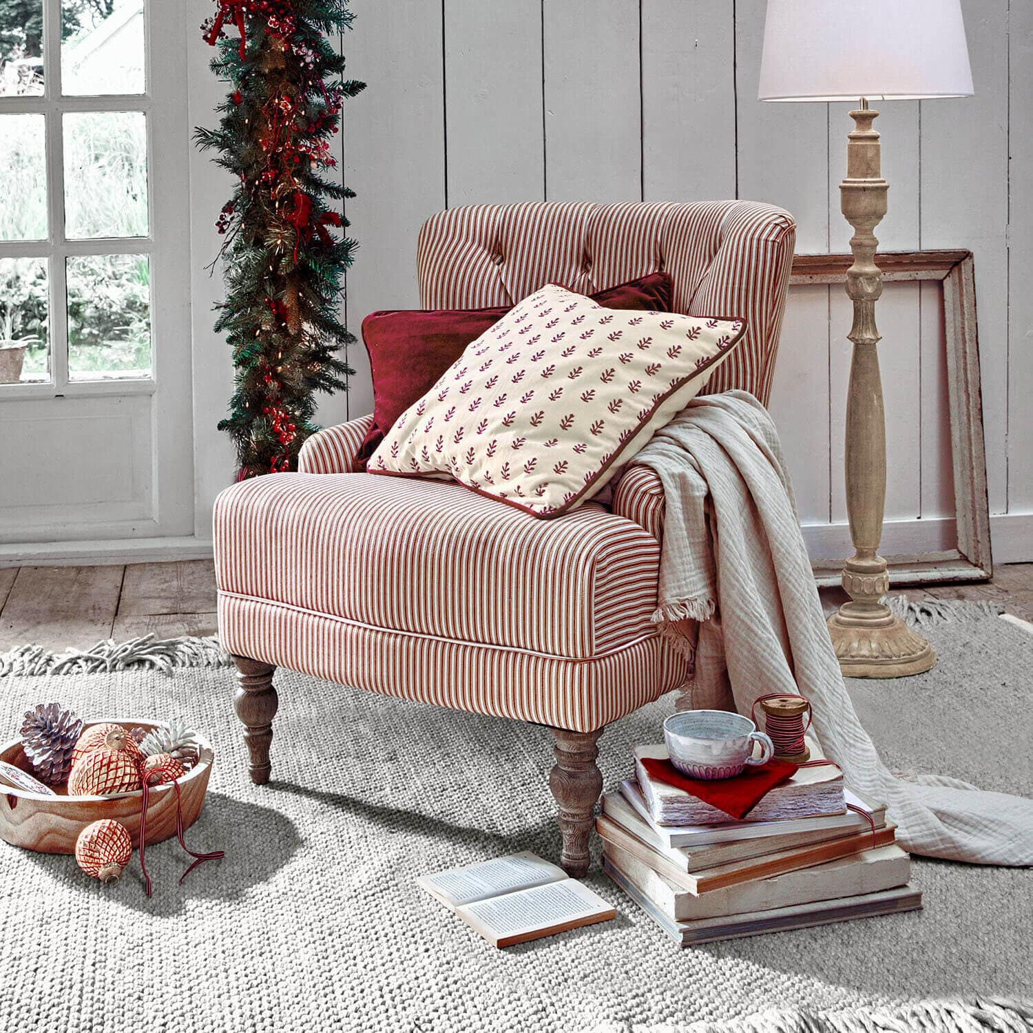 Fauteuil Amuran Fauteuil rayé en tissu rouge et blanc avec coussins et lampe dans un intérieur chaleureux