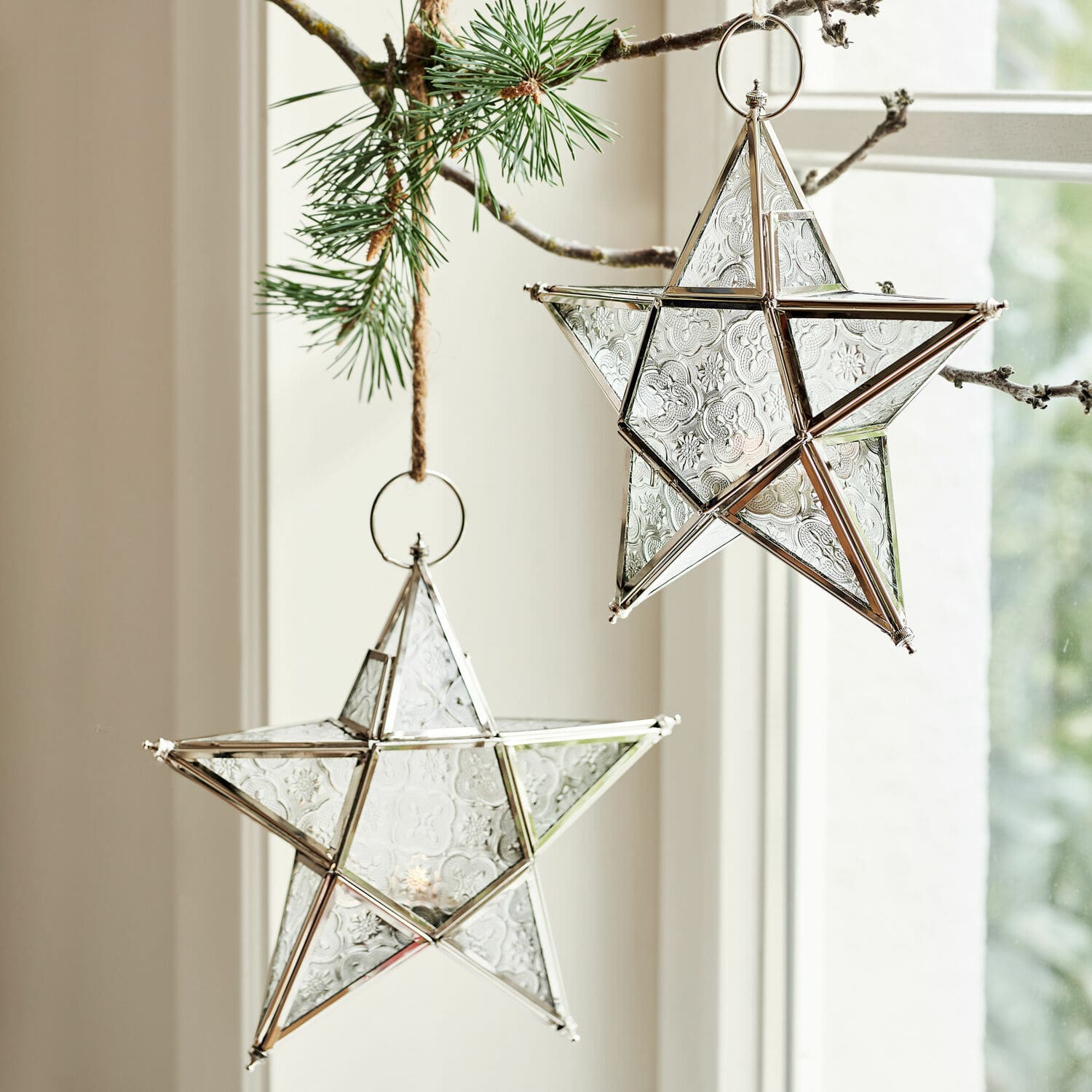 Lot de 2 photophores Kian Étoiles décoratives en verre avec cadre métallique argenté suspendues à une branche de pin