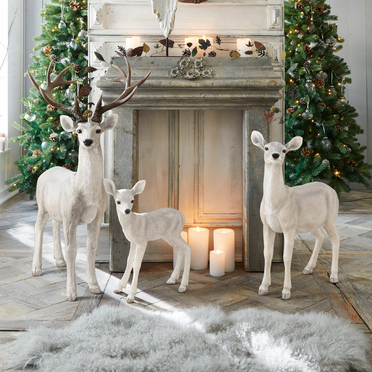Cerf avec biche et faon Olsen Figurines décoratives blanches de cerfs en matériau devant une cheminée avec bougies et sapins de Noël