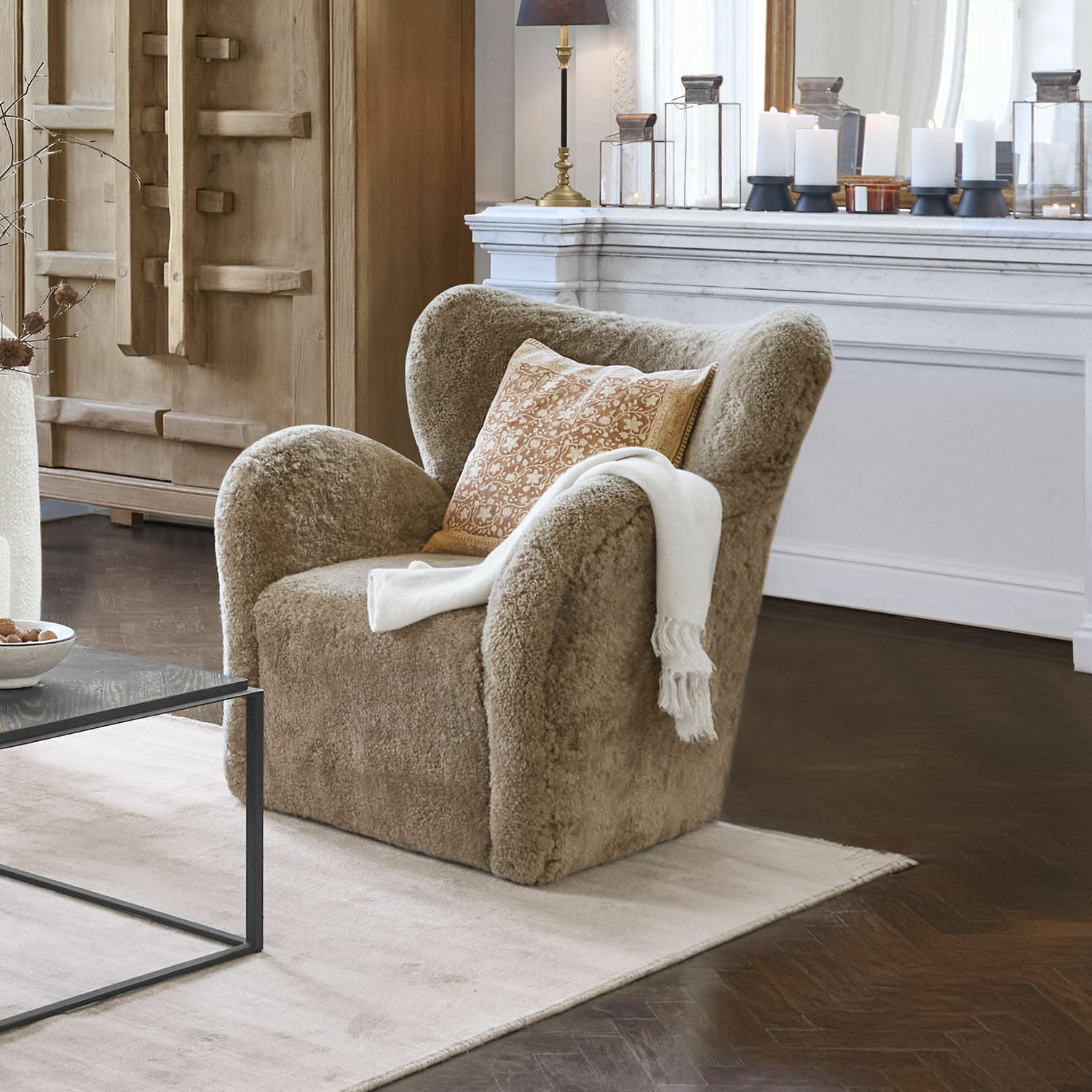 Fauteuil Ambrécourt Fauteuil beige en tissu doux avec coussin et plaid blanc dans un salon élégant