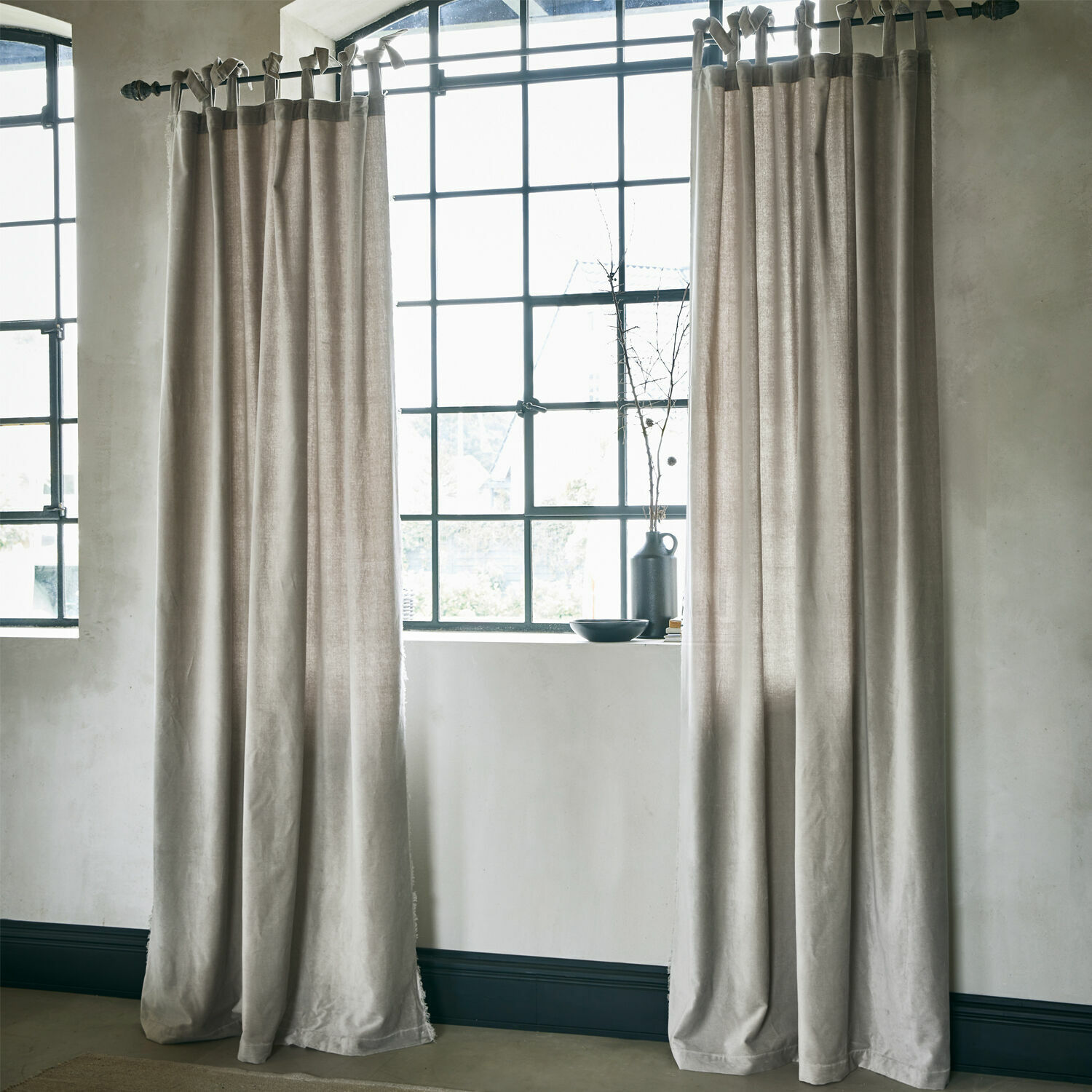 Rideau Bagujo Rideaux beiges en tissu naturel suspendus devant une grande fenêtre, décoration intérieure élégante et douce.