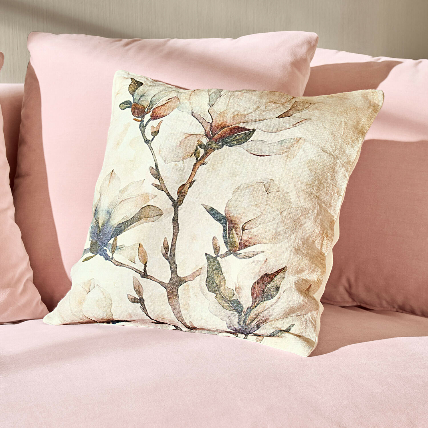Housse de coussin Aurélines Coussin en lin avec motif floral posé sur un canapé rose, décoration douce et élégante pour salon