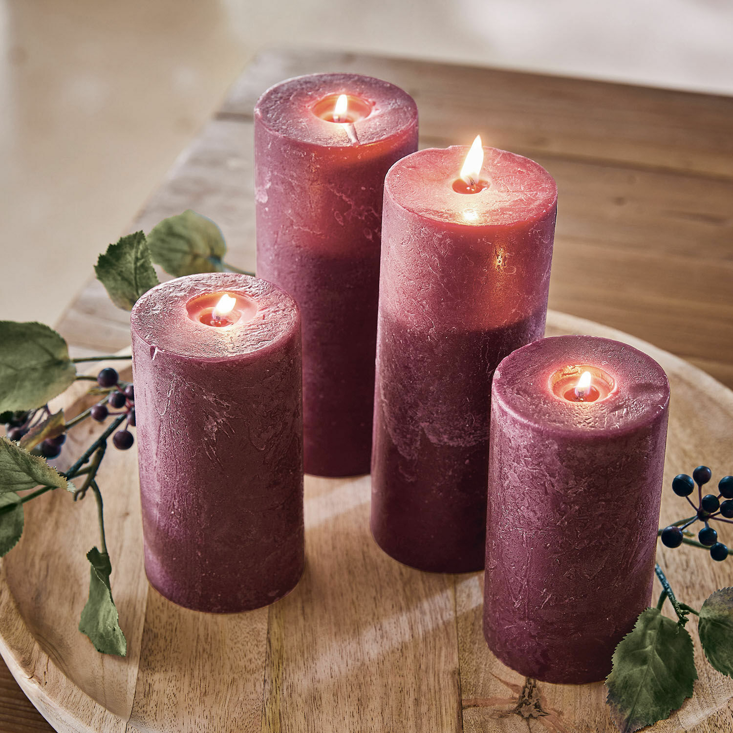 Lot de 4 bougies Berekua Quatre bougies violettes en cire sur un plateau en bois avec décor de feuilles et baies
