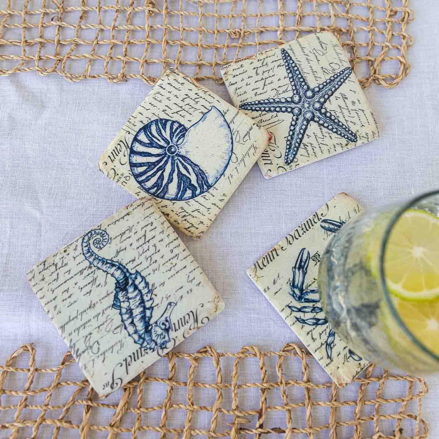 Ensemble de quatre dessous de verre en pierre avec motifs marins bleus et texte vintage sur fond clair