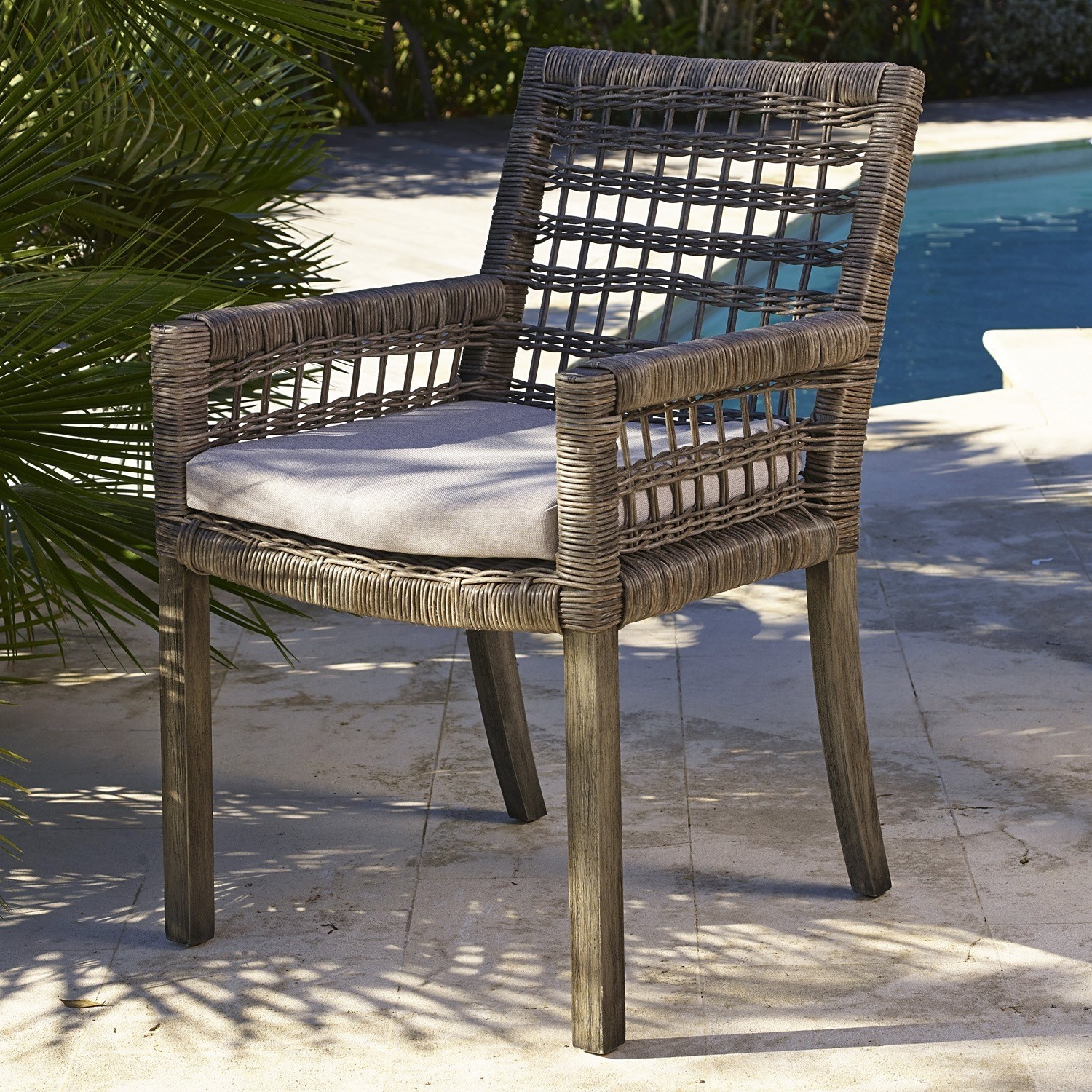 Chaise Farell Chaise de jardin en rotin gris avec coussin gris clair au bord de la piscine